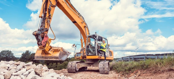 Chantier de construction en ext&eacute;rieur avec pelleteuse hydraulique orange en action