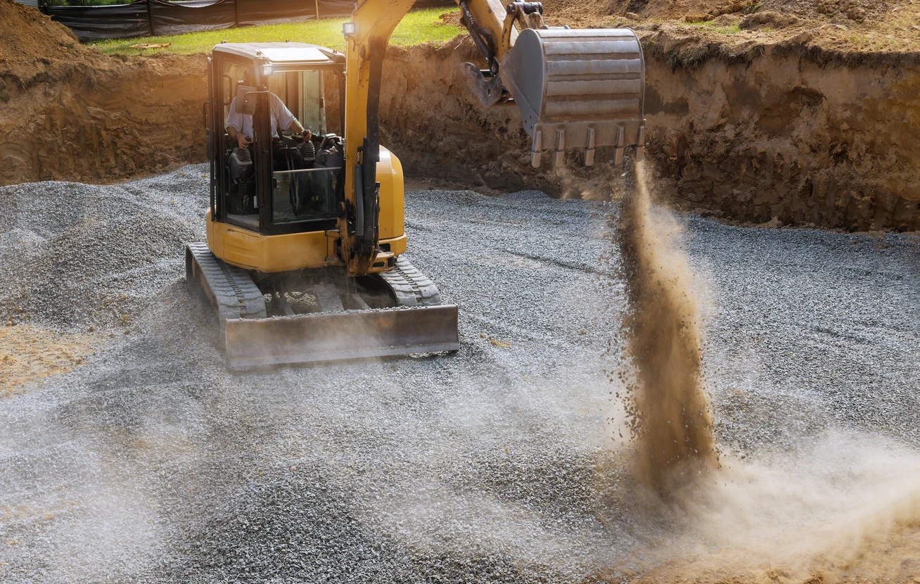 Chantier de terrassement en extérieur avec pelleteuse compacte jaune sur chenilles en fonctionnement