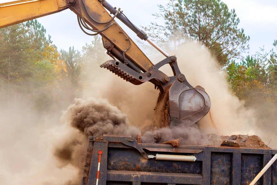 Chantier de terrassement en extérieur avec pelleteuse hydraulique déchargeant de la terre dans une benne de camion