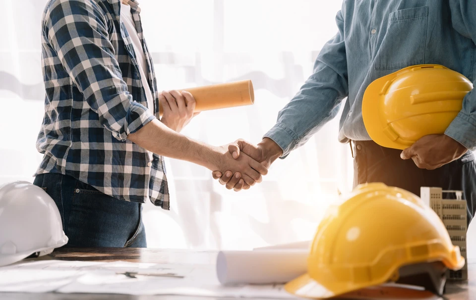 Homme en chemise à carreaux bleue tenant une tablette numérique sur un chantier de construction extérieur