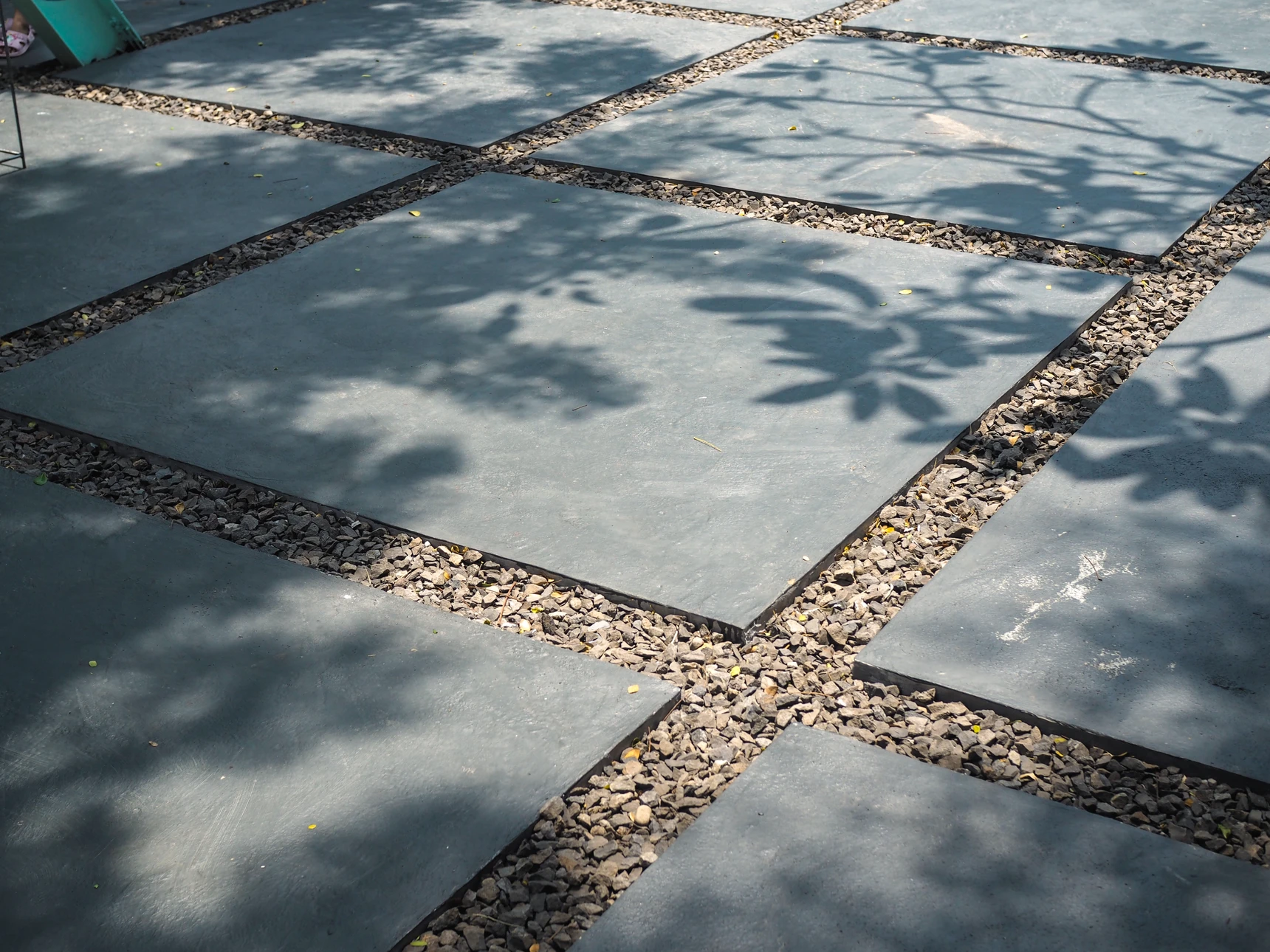 Gros plan professionnel d'une allée extérieure fraîchement aménagée recouverte de gravillons de couleur claire (beige ou gris clair), avec quelques pavés ou délimitations en bordure. La surface de gravillons est nettement visible et bien uniforme, illustrant un travail de qualité d'aménagement extérieur réalisé par un terrassier.